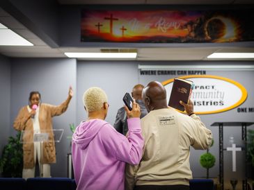 People worshiping in a church with raised hands and a speaker at the podium.