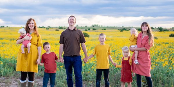 Family holding hands in a line in front of a field of yellow flowers in Snowflake AZ