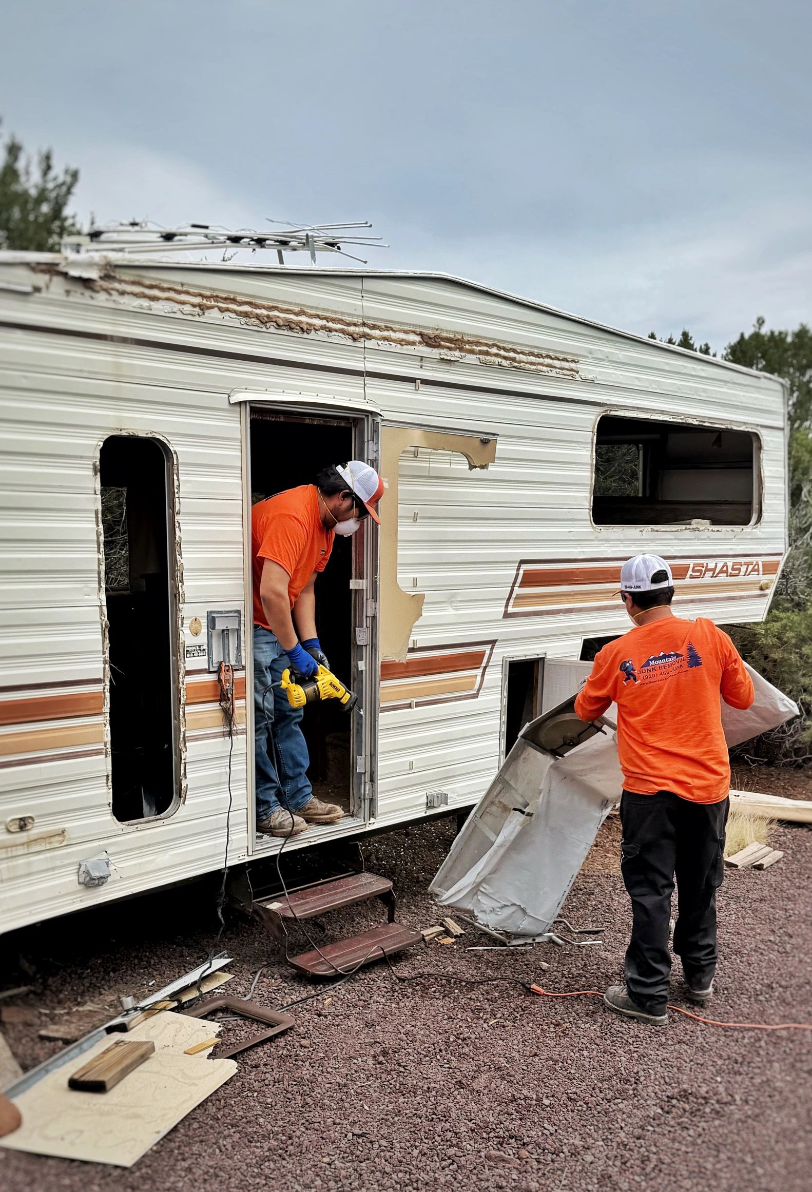 2 crew members doing small demolition on a trailer RV in 