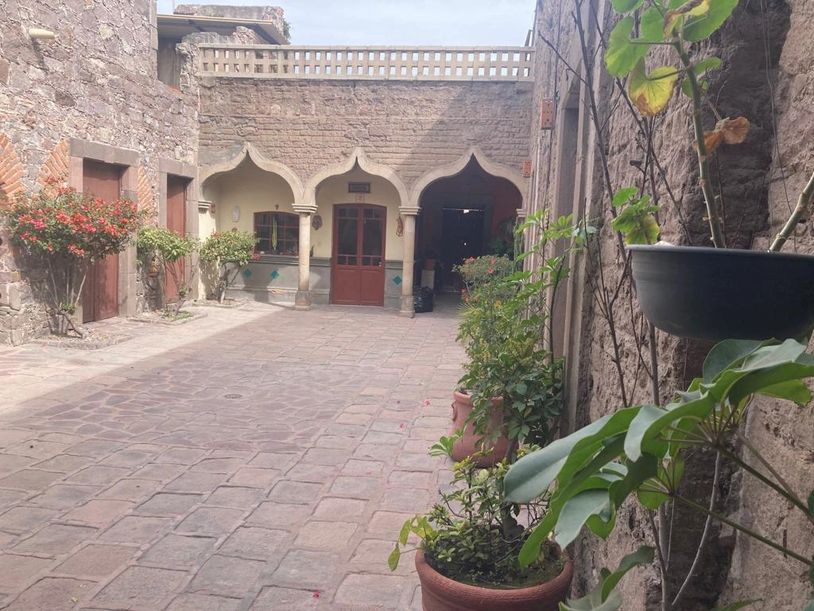 Traditional courtyard with stone walls, arches, and potted plants.