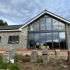 Modern house under construction with large glass windows and concrete blocks