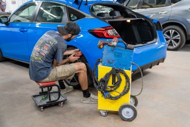 Technician working on a blue car's rear light.