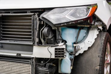 Close-up of a damaged car front with missing bumper.