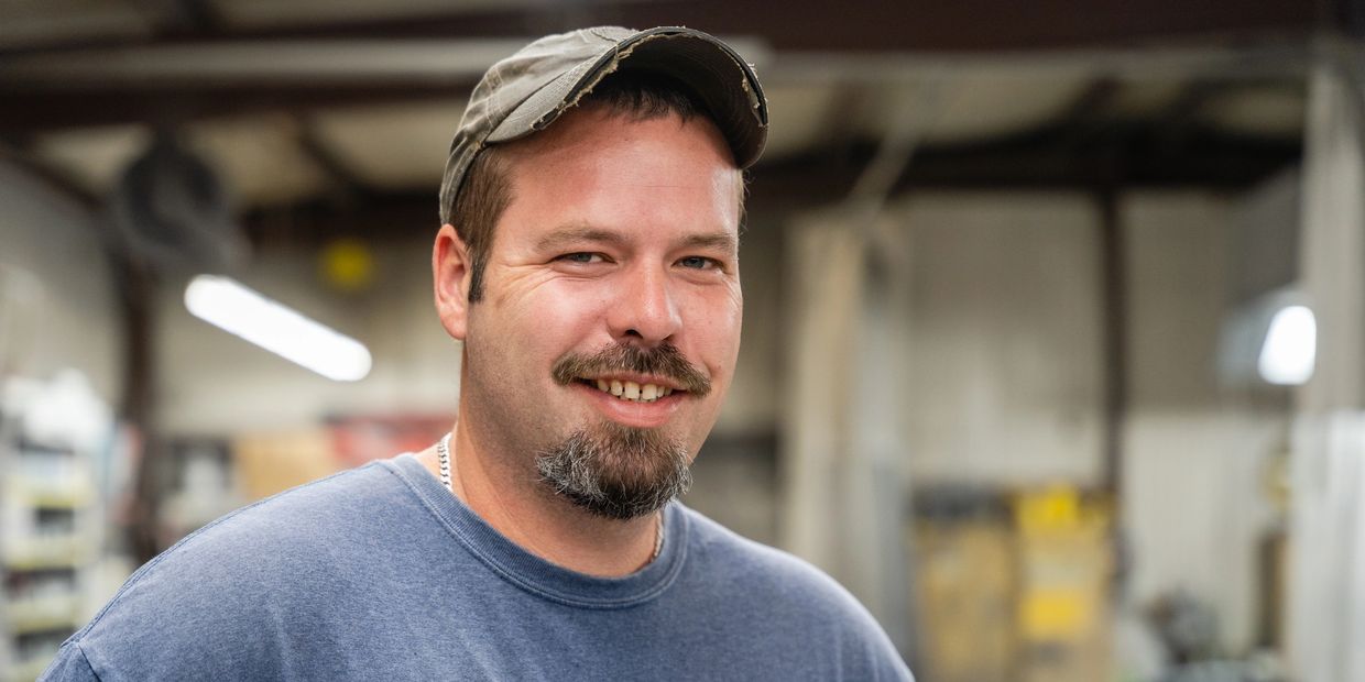 Man in a cap smiling in a workshop.