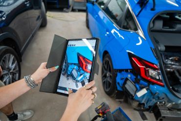 Person using tablet for car repair diagnostics.