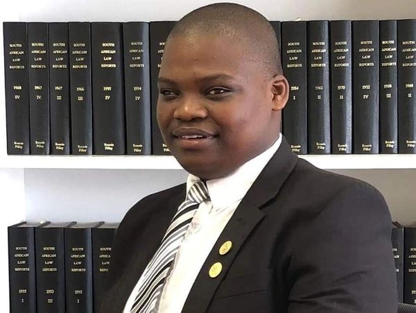 a smiling man wearing a black suite