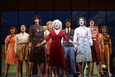 A group of actors performing a musical number on stage together.