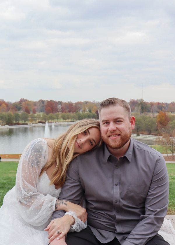 Couple sitting close by a lake with autumn colors.