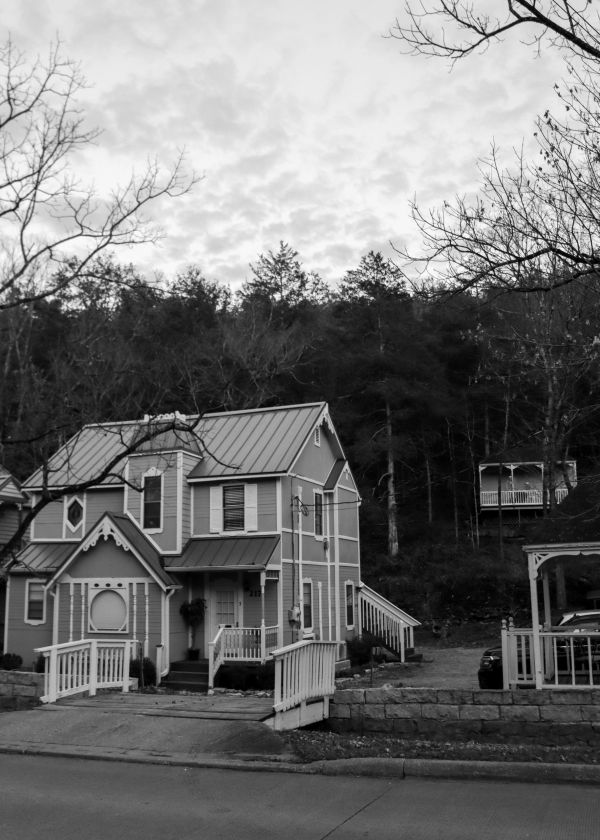 Victorian-style house in a wooded area at dusk.