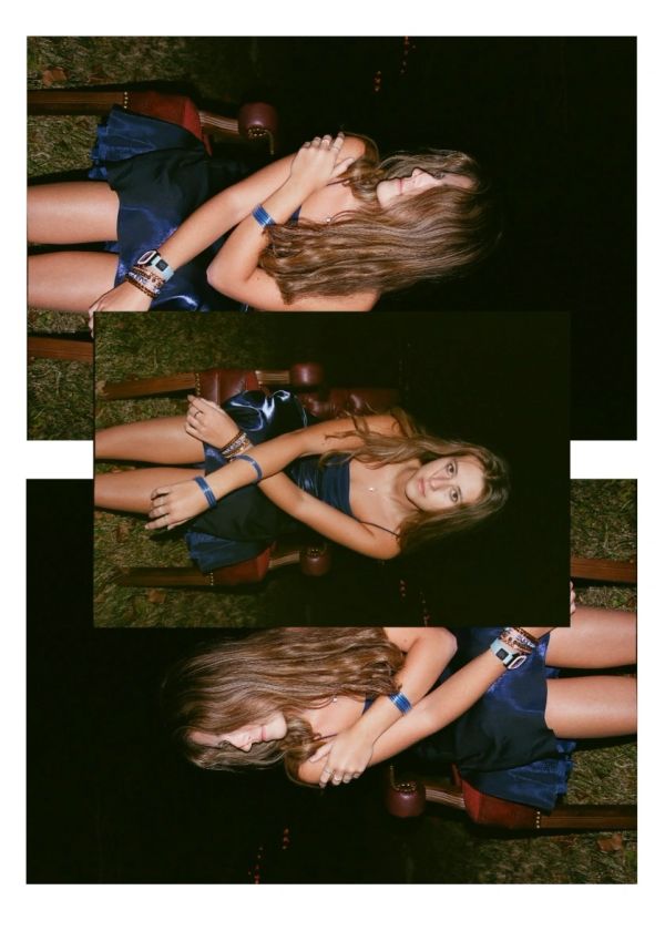 Young woman sitting outdoors at night in a blue dress.