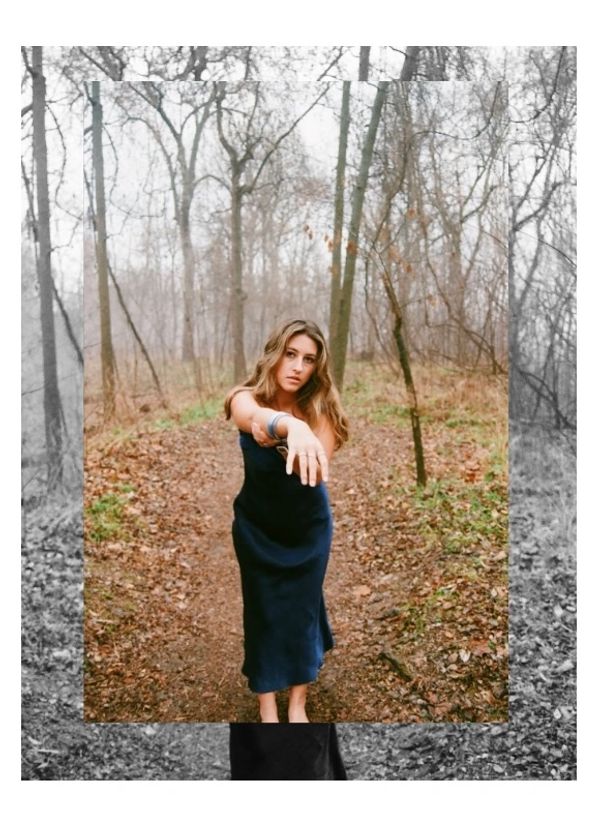 Woman in blue dress reaching out in the forest.