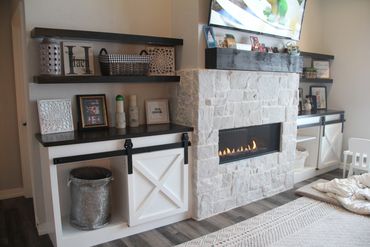 Custom X sliding barn door on base cabinetry and stained wood tops to match floating shelves