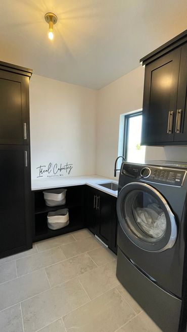 Stained maple cabinetry featuring hamper space and broom storage behind tall cabinet door