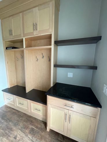 Side entry mudroom with contrasting shelves, cabinetry, and countertops