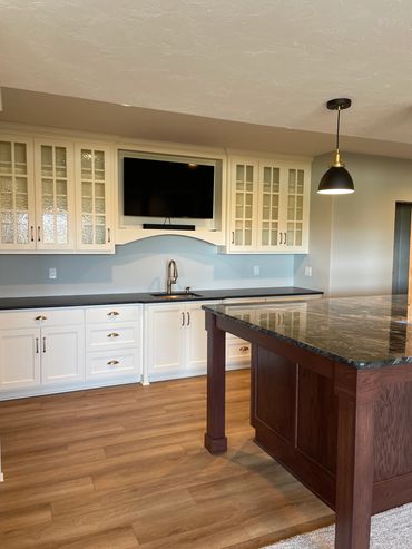 Large basement bar with painted glass uppers and oak island 