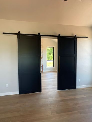 Three paneled black barn doors with brushed gold hardware