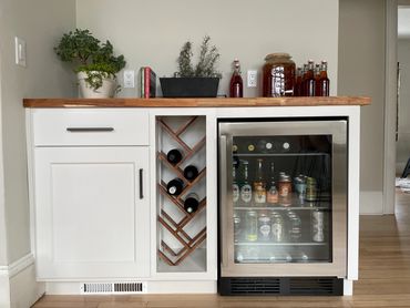 Custom maple wine rack in painted dry bar cabinetry with a butcherblock countertop