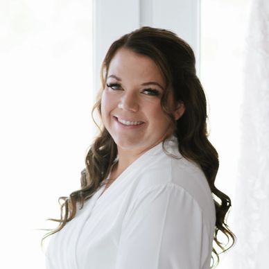 A smiling woman with long wavy hair in a white robe.