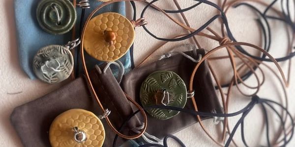 Handcrafted pendants with nature-inspired designs on leather cords.