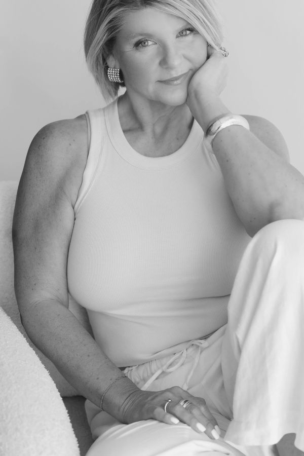 Black and white portrait of a woman smiling gently, seated comfortably.