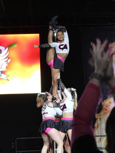 Cheerleader performing a high stretch stunt during a competition.