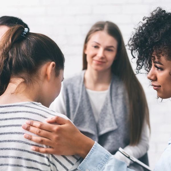 A woman comforting another in a supportive group setting.