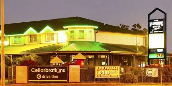 The Meander Hotel illuminated at night with signage for lunch and drive-thru.