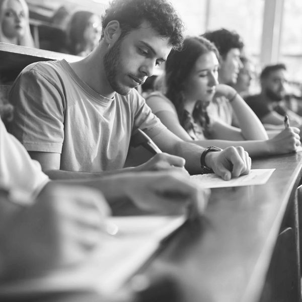 Students attentively taking notes in a university lecture hall.