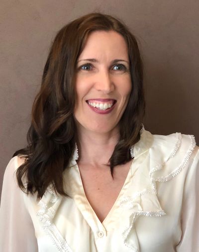 Smiling woman with brown hair in white blouse.