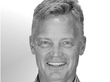 Smiling middle-aged man in striped shirt with short hair.