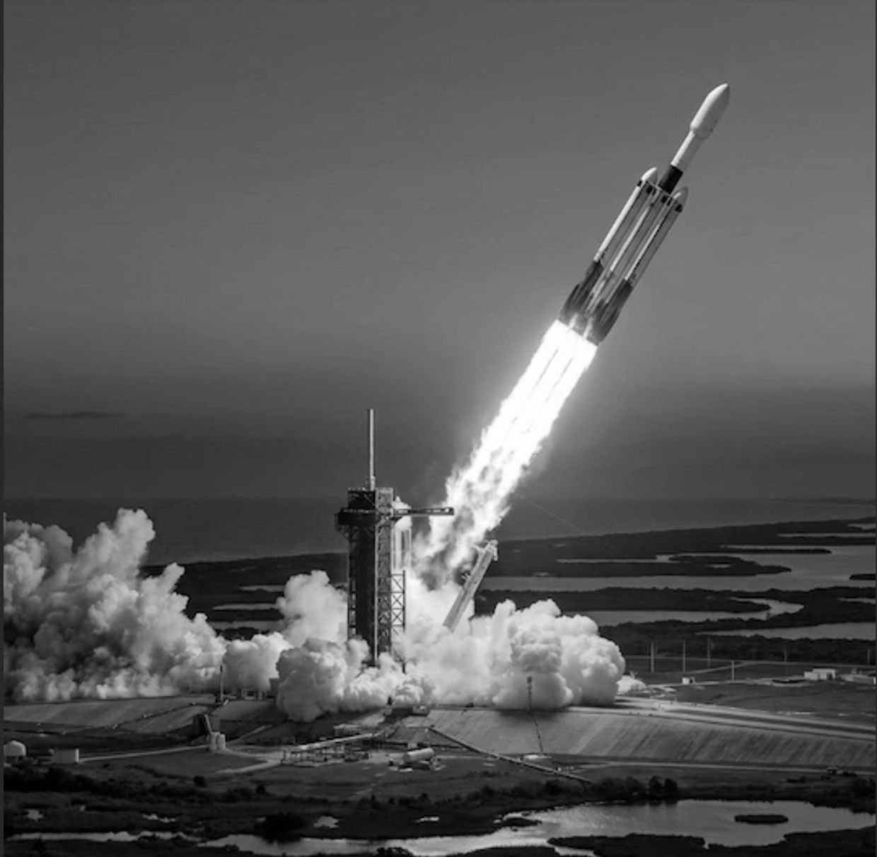 A rocket launching into the sky at sunset from a coastal launchpad.