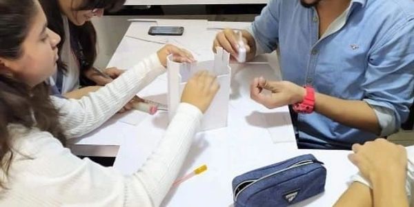 Students collaborating on a project with paper models at a table.
