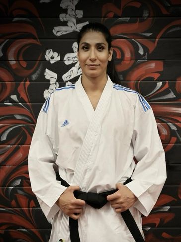 Woman in martial arts uniform with black belt.