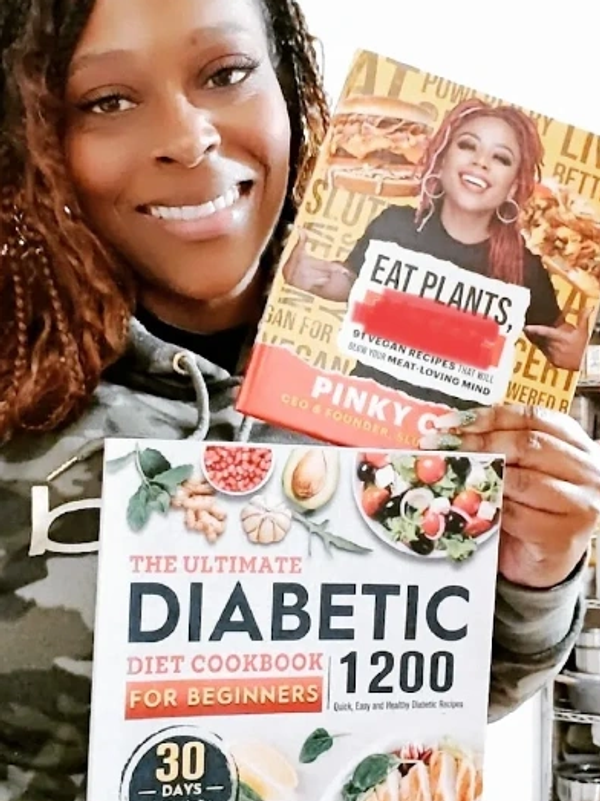 Woman holding two cookbooks and smiling.