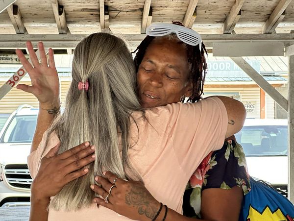 Two women praying together and hugging one another.