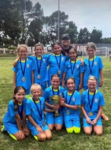 Youth soccer team posing with trophy and medals.