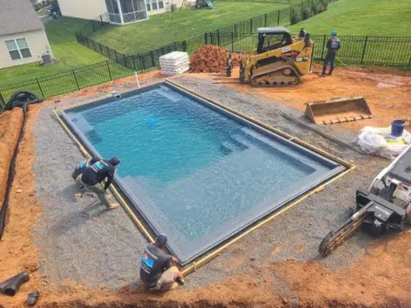 Workers installing a swimming pool in a backyard.