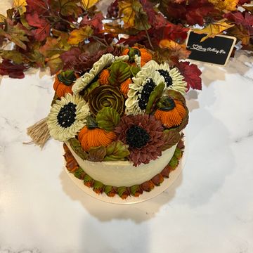 Fall cake with pumpkins, flowers, and leaves.