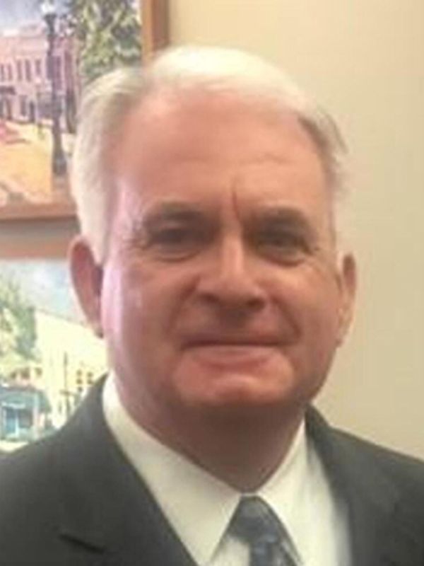 Older man in a suit smiling.