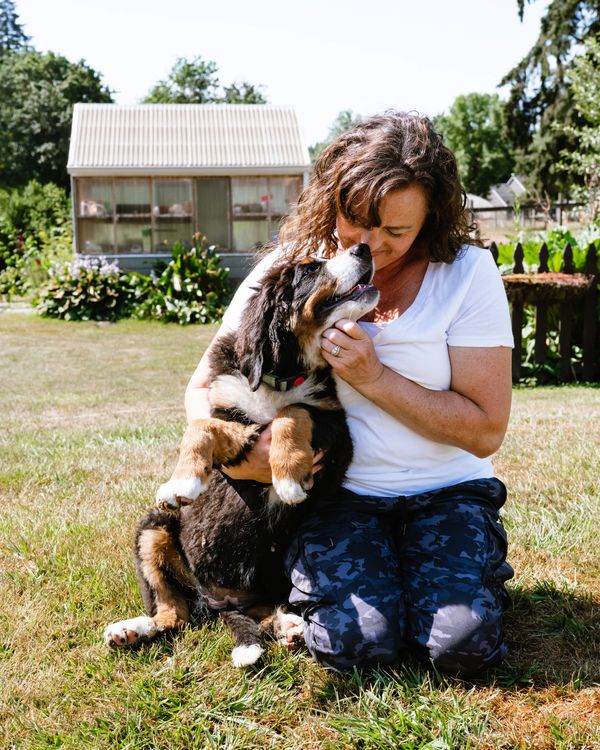 Woman lovingly embraces her dog outdoors on a sunny day.
