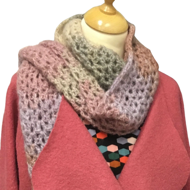 Multicolored knitted scarf draped on a mannequin with a pink coat.