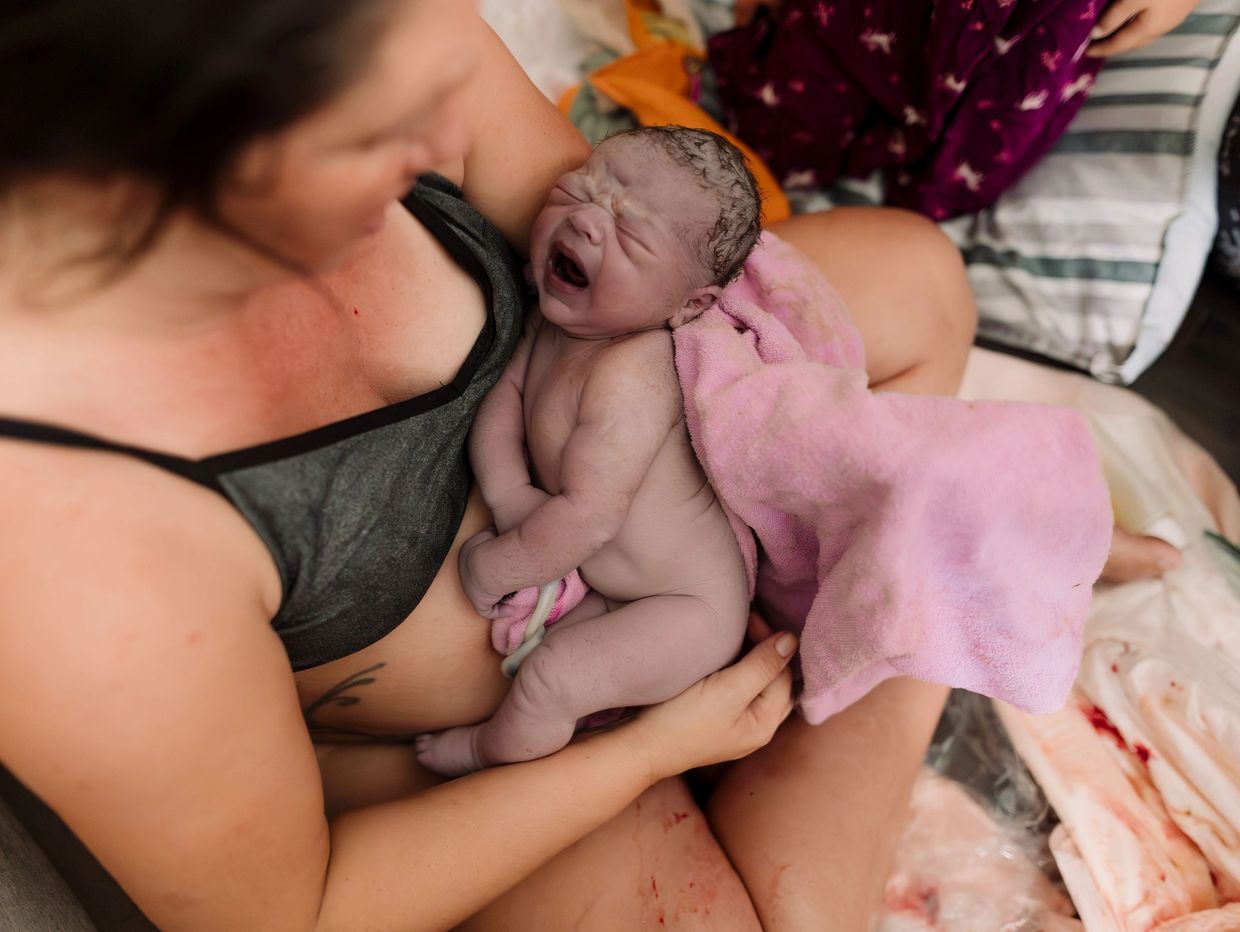 Newborn baby crying in mother's arms after birth.