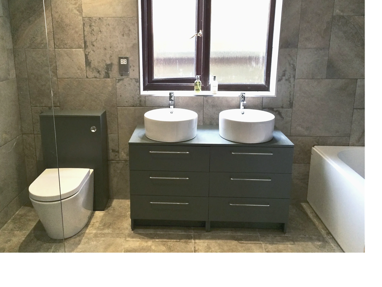 Modern bathroom with gray tiles, dual sinks, and a toilet.