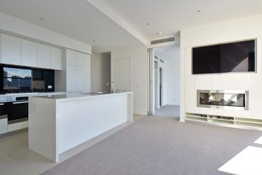 Modern kitchen and living room with fireplace and TV.