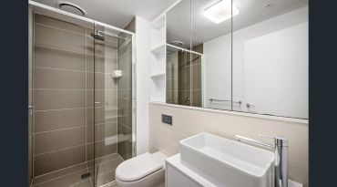 Modern bathroom with glass shower and white fixtures.