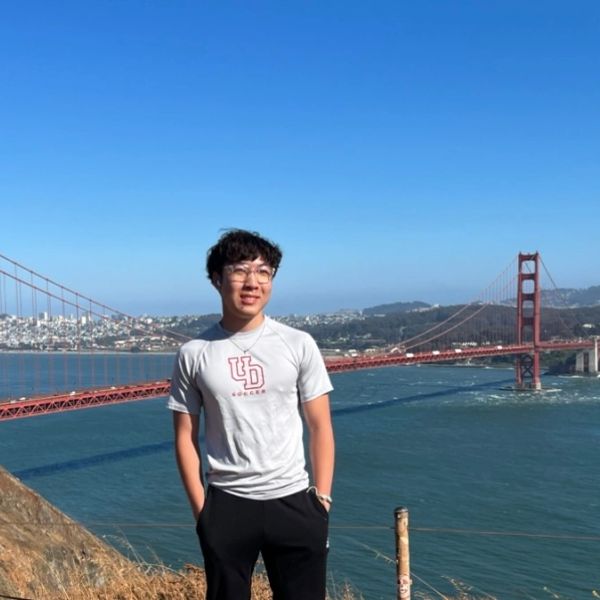 Young man standing near the Golden Gate Bridge with a clear blue sky.
