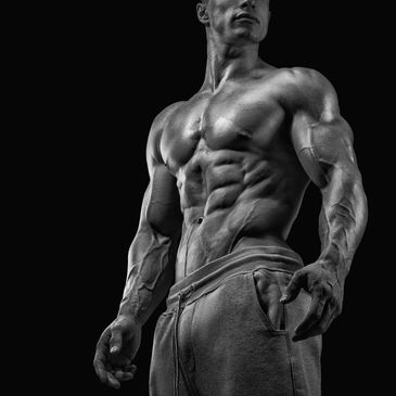 Muscular man showing defined abs and arms in black and white.