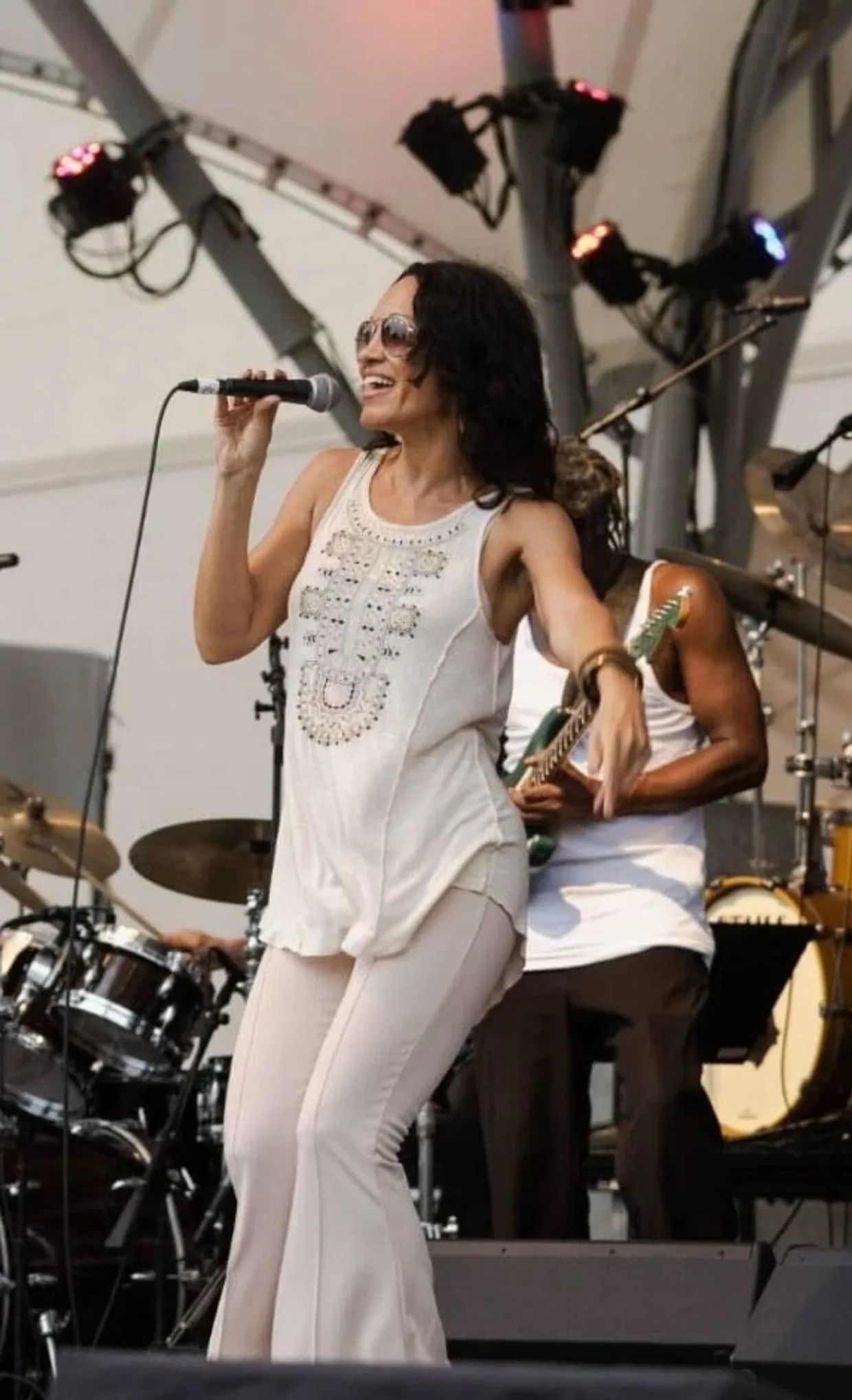 A female singer joyfully performs on stage with a band.