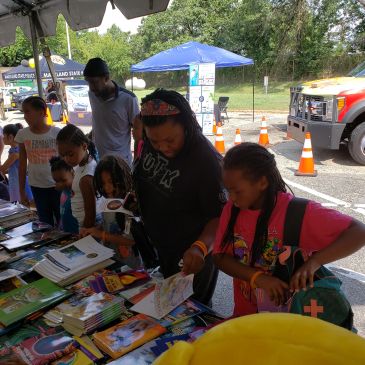 People browsing books at an outdoor event booth.