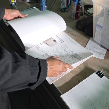 Person reviewing printed documents on a desk with office supplies.